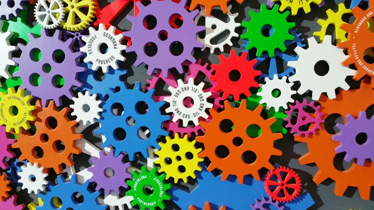 Overhead view of colourful interlocking gears in purple, green, orange, and blue, symbolising a connected content system