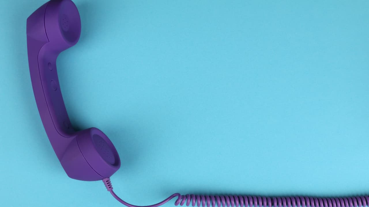 A purple vintage telephone handset resting on a teal background, symbolising a distinct personal voice