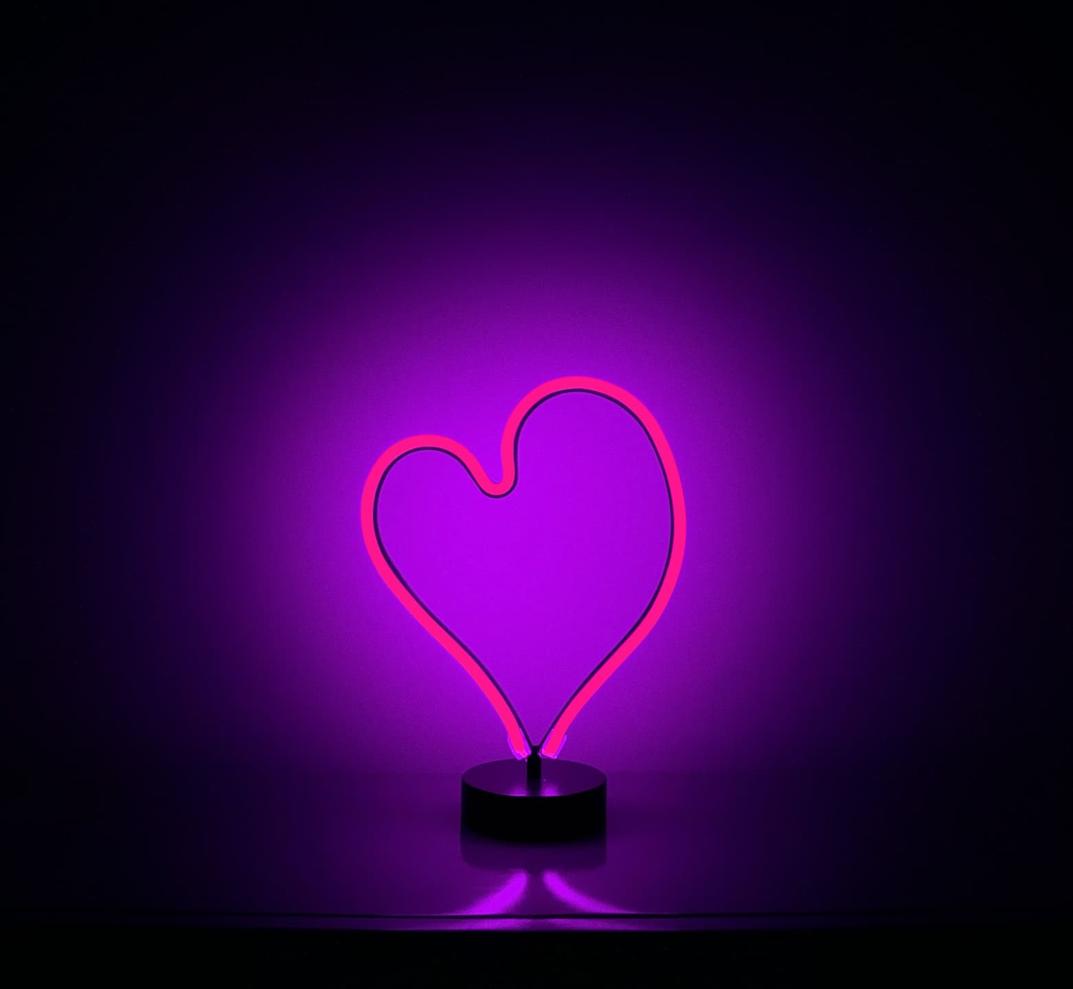 A pink neon sign glowing in a dark room