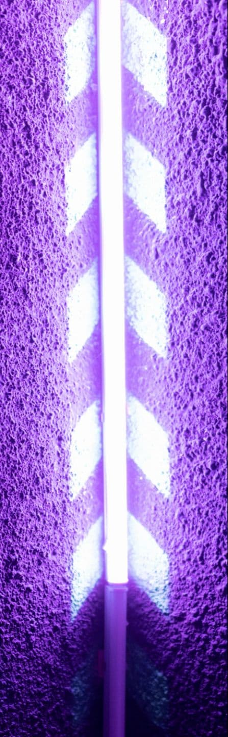 Glowing purple neon arrows pointing upward on a textured wall
