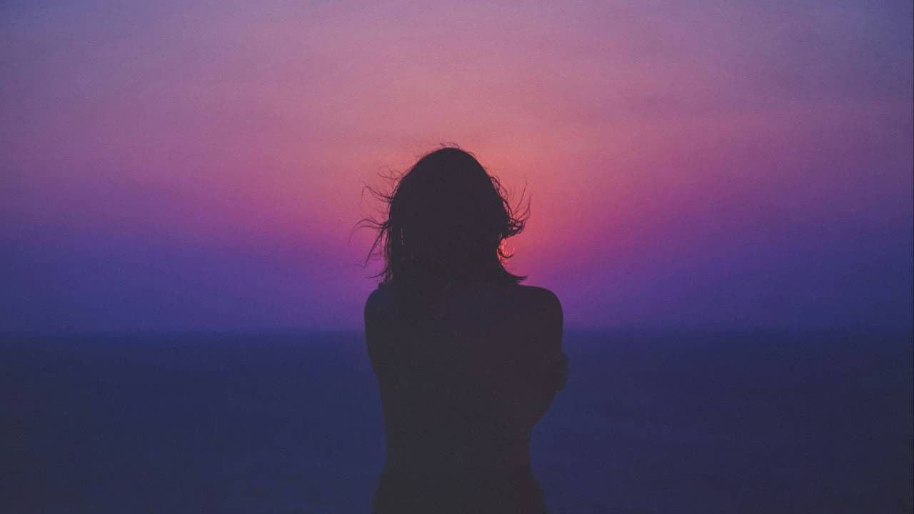 Silhouette of a person against a dusky pink and purple sky